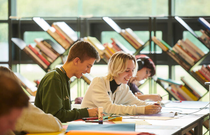 Students sitting at a table creating coursework