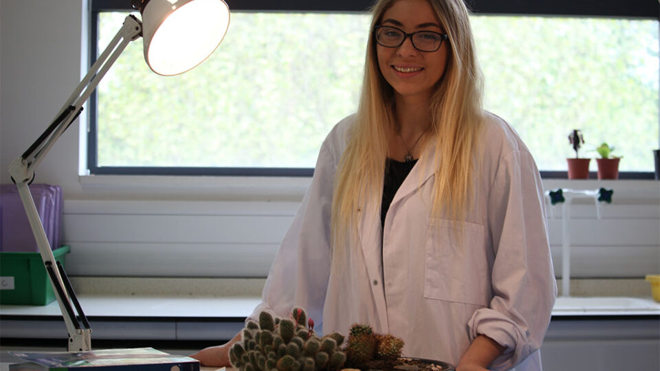 Photograph of a biology student with books and some plants.