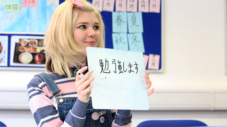 Photograph of a Japanese student holding up a card