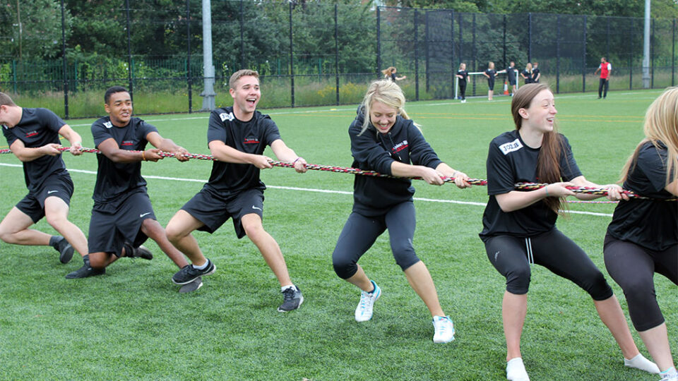 Photograph of students pulling a rope in the sports field.